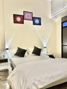 dwa łóżka w sypialni z trzema zdjęciami na ścianie w obiekcie Holy River Stays w mieście Waranasi