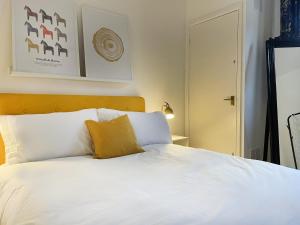 Una cama con sábanas blancas y una almohada amarilla. en 3 bed home in Cheltenham Town Centre with FREE PARKING for 1 car en Cheltenham