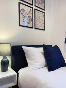 1 dormitorio con 1 cama con almohadas azules y blancas en 3 bed home in Cheltenham Town Centre with FREE PARKING for 1 car en Cheltenham