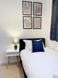 3 bed home in Cheltenham Town Centre with FREE PARKING for 1 car في تشلتنهام: غرفة نوم بسرير وطاولة مع مصباح
