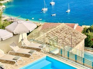 a pool with chairs and umbrellas and the ocean at Villa Tesoro Kalami with private pool by DadoVillas in Kalami