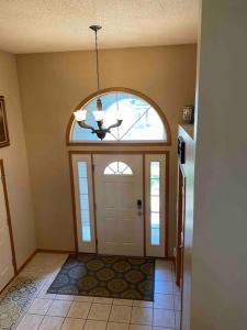 a hallway with a door with a window and a chandelier at Beautifully Furnished 5-Bedroom in Rochester