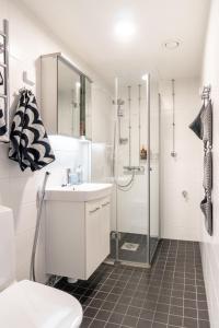La salle de bains blanche est pourvue d'une douche et d'un lavabo. dans l'établissement Kodikas asunto Tikkurilassa, à Vantaa