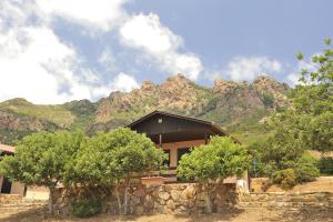 a house with a stone wall and mountains in the background at Villaggio Camping Tesonis Beach in Terten&igrave;a