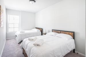 2 camas en una habitación con sábanas blancas y toallas en La Vida Loca, en Baton Rouge