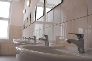 a row of sinks in a bathroom with mirrors at Mogyorodi Hostel in Budapest