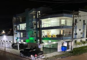 Fort Poseidon, venha desfrutar do conforto de sua casa a 700 metros da praia do Atalaia na rua do Atalho, apartamento mobiliado novo, duas suítes, mais banheiro social, varanda, sala de estar e jantar, lavanderia e cozinha, vista para as dunas e praia في سالينوبوليس: شاحنة متوقفة أمام مبنى في الليل