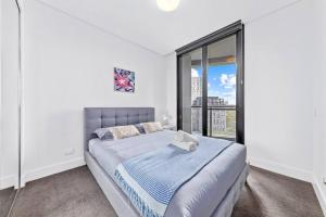 een slaapkamer met een bed en een groot raam bij Warm and cozy 3 Bed APT in Sydney