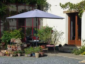 un parapluie bleu devant une maison avec des plantes dans l'établissement Gîte Périssé, à Libaros