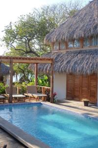 une villa avec une piscine et un toit de chaume dans l'établissement Still Salty Escape, à El Viejo