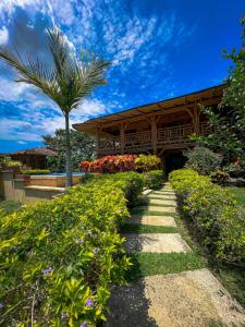a building with a palm tree and a walkway at Hotel Campestre Campos Verdes in Roldanillo