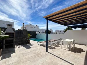 a patio with a table and chairs and a swimming pool at Casa Oona in Playa Blanca