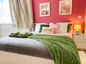 a bedroom with a bed with a green blanket on it at Modern and Comfy 1-Bedroom Flat in Wembley in London