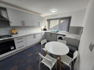 una cocina con mesa blanca y sillas. en 4 Bedroom 2 Bathroom Shared House - Near BHX and NEC, en Birmingham