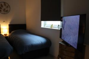 a bedroom with a bed and a flat screen tv at Happy Homes Melle Centre, Near Ghent! in Melle