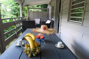 eine Schale Bananen und andere Früchte auf einem Tisch auf einer Veranda in der Unterkunft Ranch Black Horse in Les Trois-Îlets