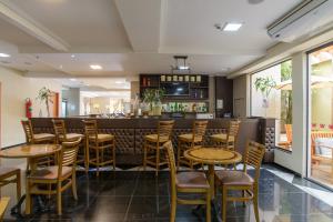 un restaurante con taburetes de madera y un bar en Faro Hotel Atibaia en Atibaia