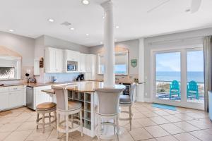 a kitchen with white cabinets and a large island with bar stools at Valhalla in St. George Island
