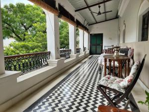a balcony with a table and chairs and windows at Vijai Mahal - A Colonial Homestay in Ajmer