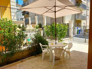 una mesa y sillas con una sombrilla en el patio en Villino Maria Pia, appartamento in villino in centro storico L'Aquila en LʼAquila