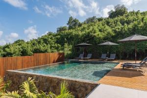 a pool with chairs and umbrellas in a backyard at Pousada Maria Flor in Fernando de Noronha