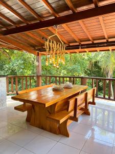 une table en bois sur une terrasse avec un lustre dans l'établissement Pousada Casa Mucugê, à Porto Seguro