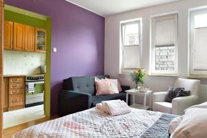 a bedroom with purple walls and a bed and a couch at P&O Apartments Bielany in Warsaw