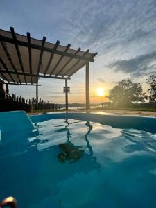 a swimming pool with a sunset in the background at Chalé Mirante, piscina, cachoeira, lago e vista espetacular in Alexânia