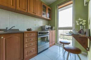 a kitchen with green walls and wooden cabinets and stools at Bielany P&O Apartments in Warsaw