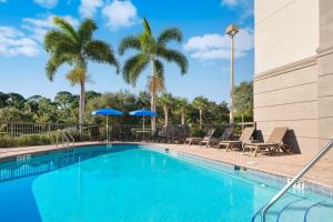 a swimming pool with chairs and palm trees at Hampton Inn Melbourne-Viera in Melbourne