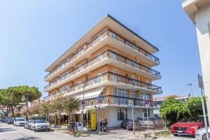 a tall building with cars parked in a parking lot at Hotel Ribot in Rimini