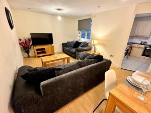 a living room with a black couch and a tv at April Disc - Long Stay - Contractors in Swindon