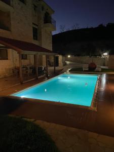 a swimming pool in front of a building at night at Softades Cottage in Omodos