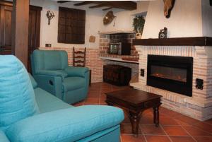 sala de estar con sillas azules y chimenea en Casa Rural LA BODEGA, ofrece cata de vino gratis, en Horche
