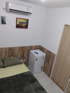 Habitación pequeña con cama y nevera pequeña. en HORTA DO TOMATE, en Bombinhas