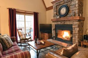a living room with a fireplace with a clock above it at Plateau B - Mont-Tremblant in Mont-Tremblant
