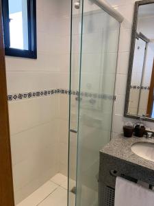 a glass shower in a bathroom with a sink at Flat aconchegante 1508 in Goiânia