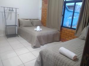a bedroom with two beds and a window at quarto 03 triplo econômico bwc exclusivo corredor in Penha