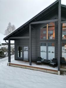 una casa con 2 sillas y un porche en la nieve en Luxury Villa Lapland, en Rovaniemi