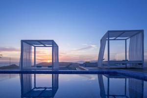 a swimming pool with a sunset in the background at Colours of Mykonos Luxury Residences & Suites in Psarou