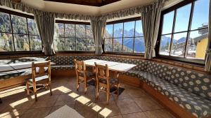 a dining room with a table and chairs and windows at Hotel Betulla in Madonna di Campiglio