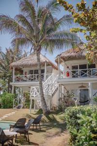 a white house with a palm tree in front of it at Coco Unlimited in Tulum