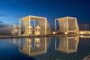 a building with a pool of water at night at Colours of Mykonos Luxury Residences & Suites in Psarou