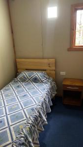 Schlafzimmer mit einem Bett, einem Tisch und einem Fenster in der Unterkunft Cabañas parcela el ciprés in Melipeuco