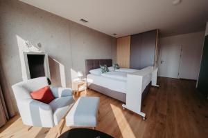 a bedroom with a white bed and a chair at RELAX APARTMENTS Hochgraßnitzberg in Spielfeld