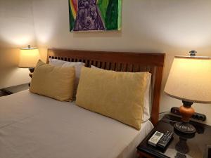 1 dormitorio con 1 cama con 2 lámparas y teléfono en Beach Front Village, en Salvador