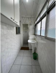 a white bathroom with a sink and a window at AP Aconchegante a 60 Metros da Praia, vista mar 302 in Praia Grande