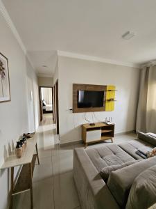 sala de estar con sofá y TV en la pared en Apartamento Completo - Algarve 203 e 204, en Patos de Minas