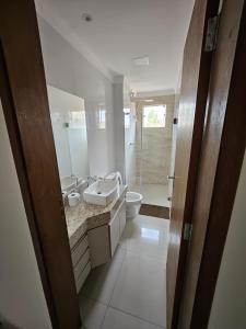 ein weißes Bad mit einem Waschbecken und einem WC in der Unterkunft Apartamento Completo - Algarve 203 e 204 in Patos de Minas