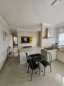 uma cozinha com uma mesa, cadeiras e um fogão em Apartamento Completo - Algarve 203 e 204 em Patos de Minas